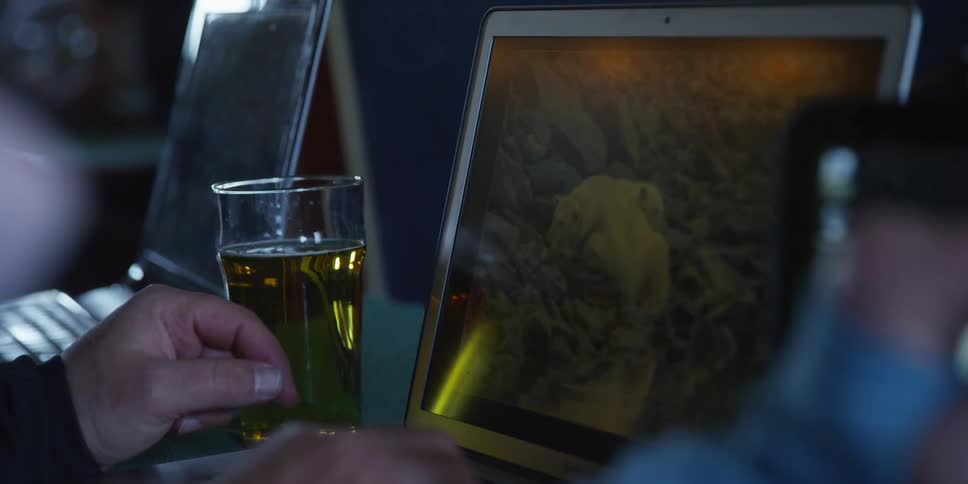 Glass of beer next to a screen