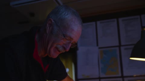 A man stands near a lamp and talks