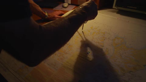 A man uses a metal compass on a map