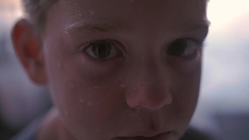 A young boy with water droplets on his face