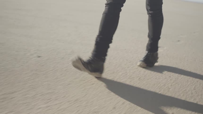 Person walking over sand on a sunny day