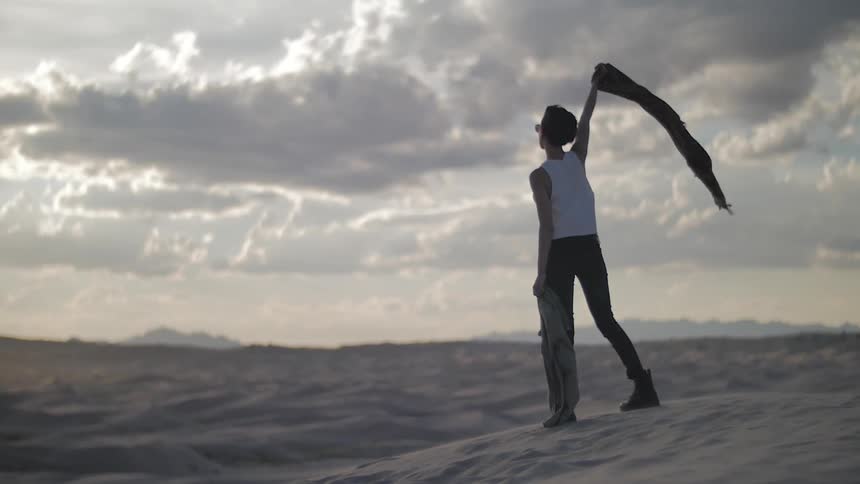 Person holding a scarf above her head on a cloudy day