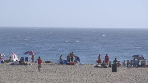 Two boys play soccer on a crowded beach