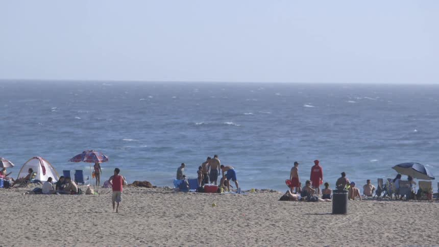 Two boys play soccer on a crowded beach