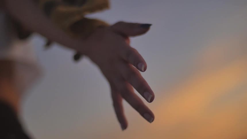 Woman with her arm outstretched on a cloudy day