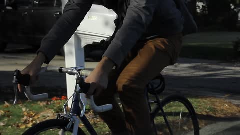 Man with messenger bag riding a bike down the street
