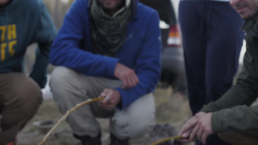 People roasting food on their sticks over an open campfire