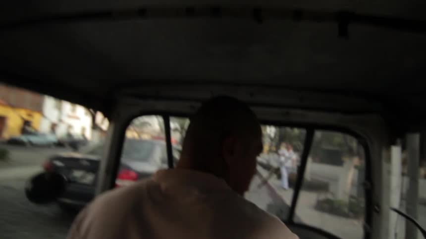 A man in a white shirt driving down the road