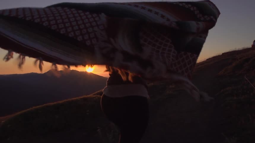 A woman is carrying a blanket in the desert