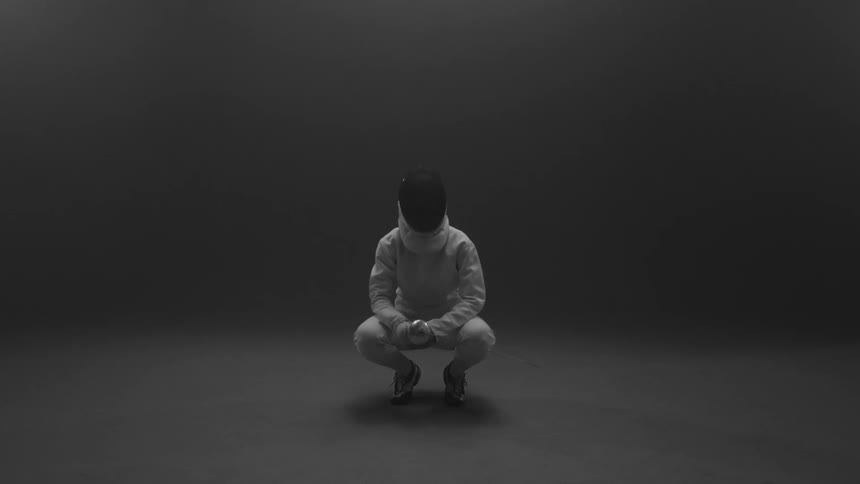A fencer holds a sword then squats