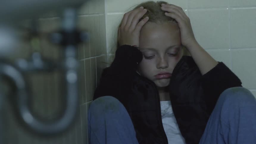A girl holding her head while sitting on the ground