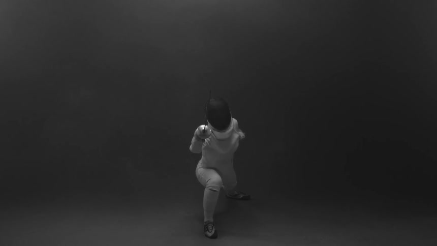 A person fencing in an empty dark room