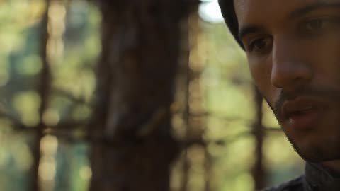 Man looking intensely at something in his hands in the woods
