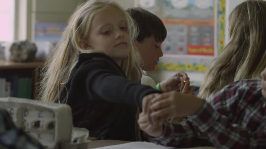 A girl bullies a boy sitting next to her in class