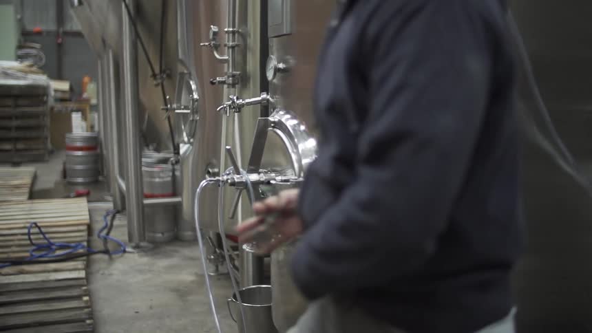 A man walks between large metal vats