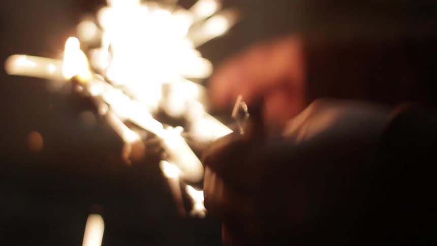 A person holding a lighter lights a sparkler