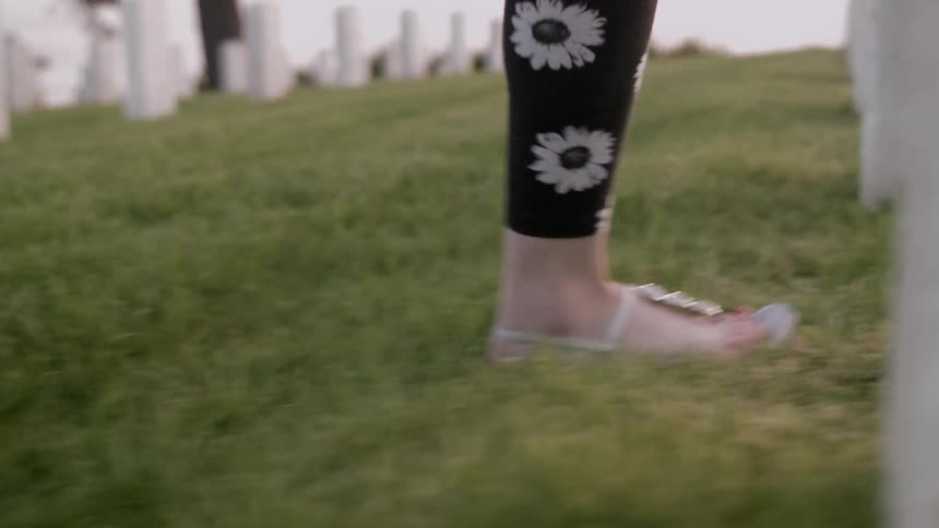 A womans feet with slippers walking on grass