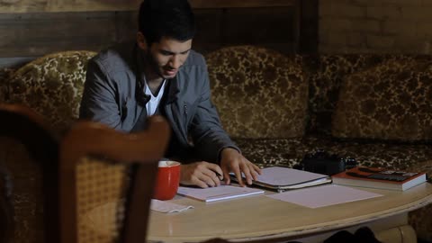 Man sitting on the sofa writes down and smiles