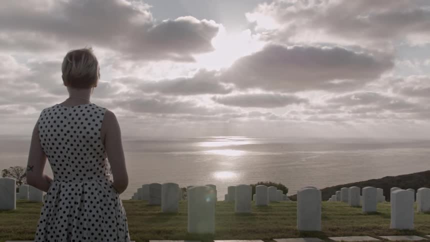 Woman standing before a large cemetery on a cloudy day