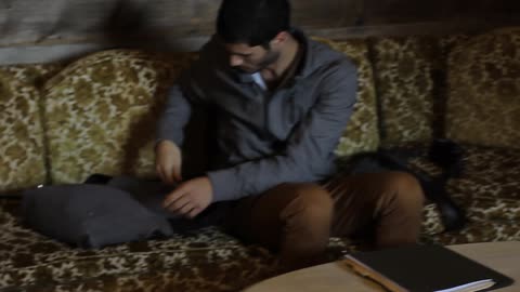 Man with camera sits down on a couch