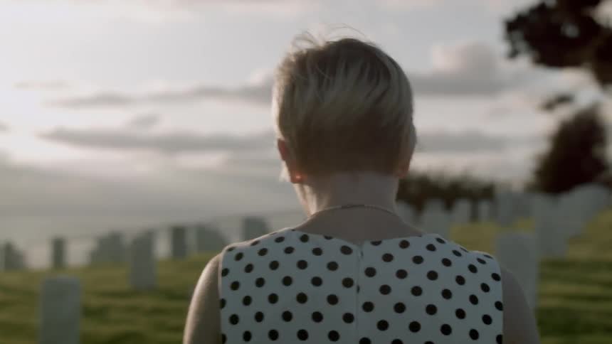 A blonde woman walks through a cemetery
