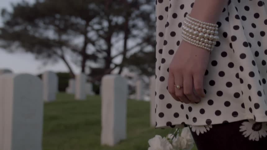 A woman stands at a grave