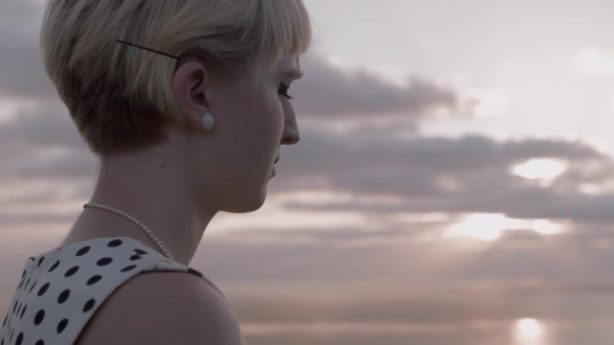 A woman stands with her eyes closed