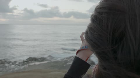 A woman taking a picture of the beach during the day