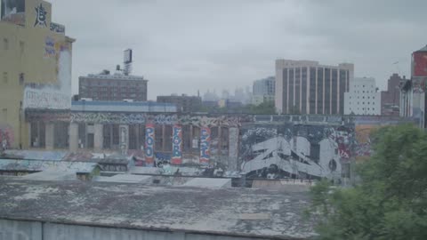 Graffitied walls are shown in a city