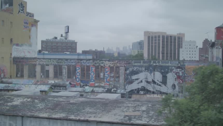Graffitied walls are shown in a city