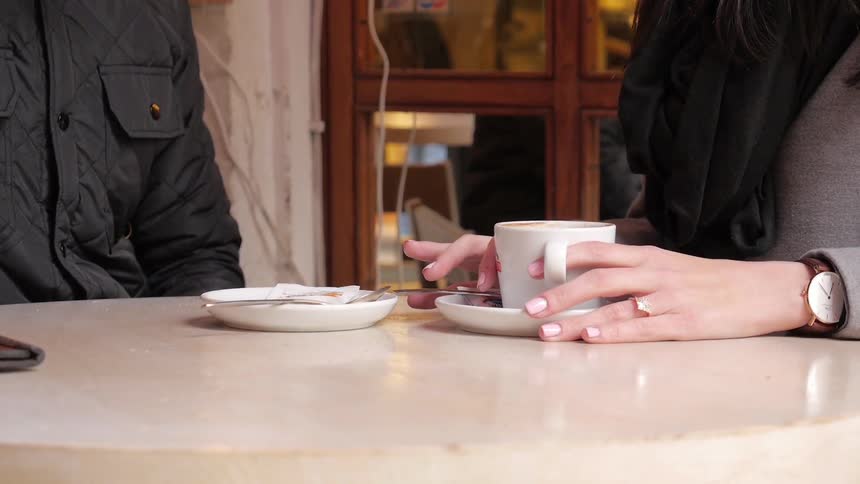 Man and woman sitting down to drink coffee together