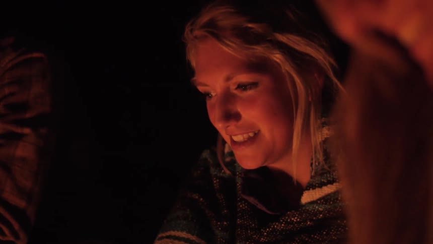 Friends sit around a campfire and talk at night