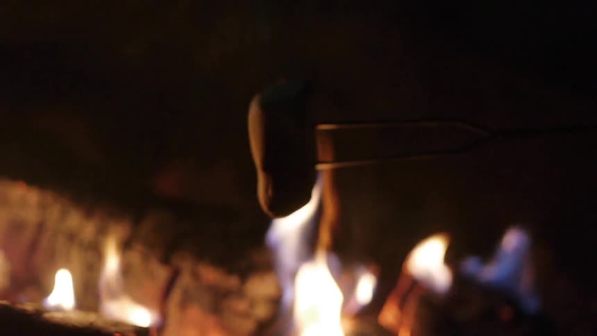 Campfire that is roasting a marshmallow at night