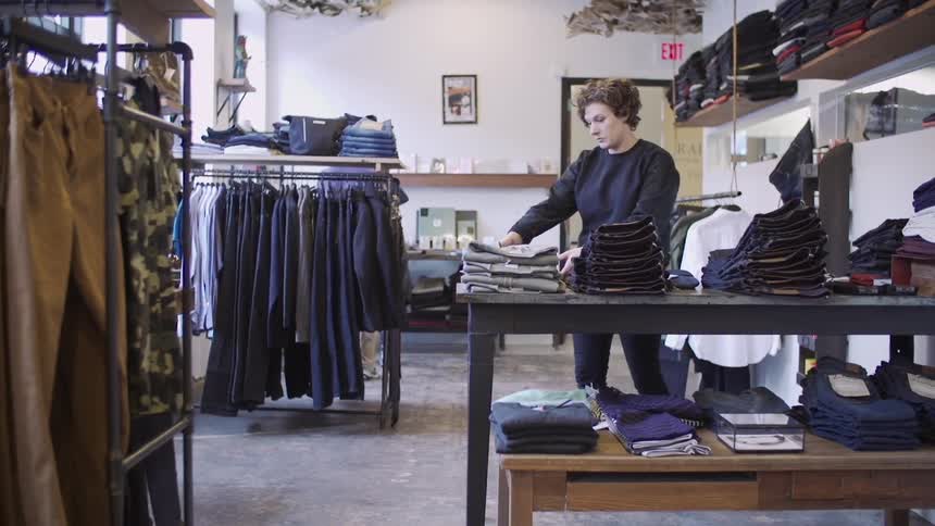 A woman arranging clothing on a table