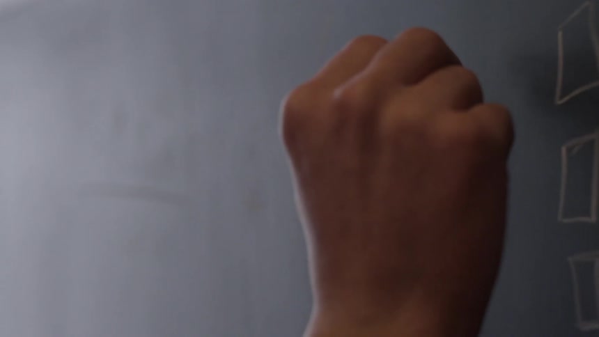 A person writing an algebra equation on a chalkboard