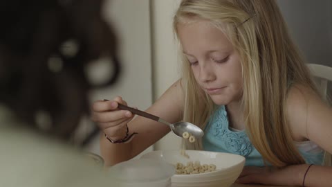 A little blonde girl eating cheerios