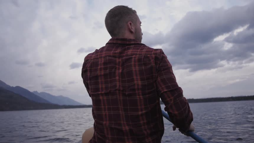 A man paddles in a kayak on a lake