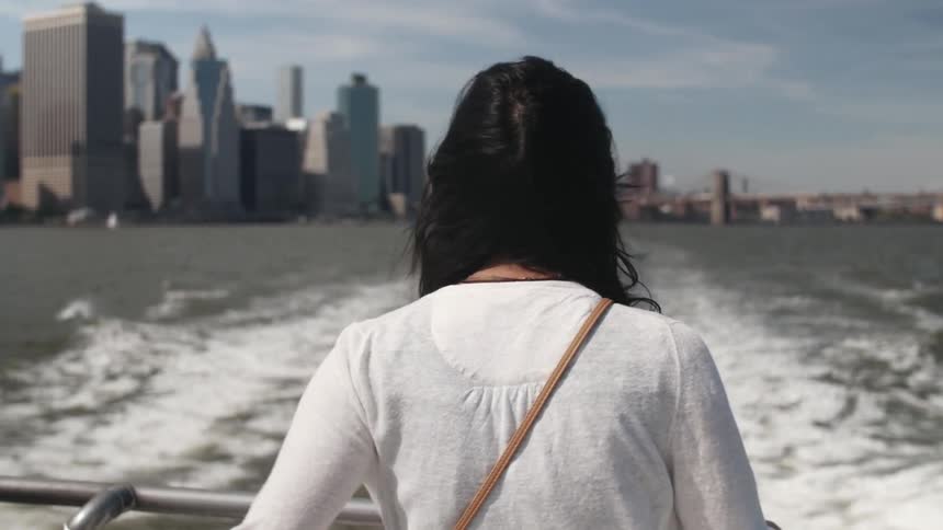 A woman riding a ferry away from a city