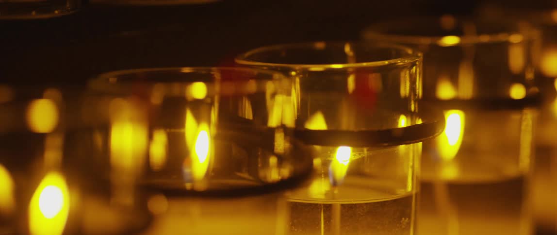 A row of glass candle holders with flickering flames