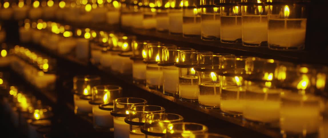 Three rows of lit candles in a dark room