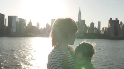 A woman and a baby in front of some water