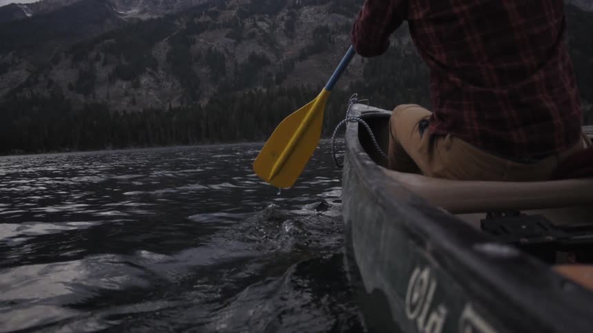 A man paddles in a kayak on a lake