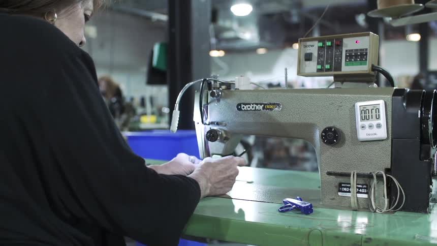 A woman working on a sewing machine in a factory