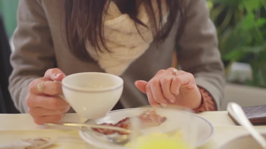 Woman eating breakfast with a  cup of tea