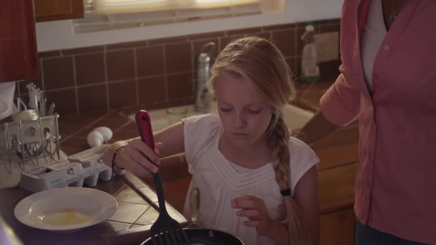 Woman and girl cooking eggs in the kitchen