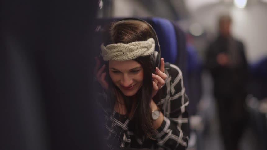 A woman with headphones laughs on public transportation