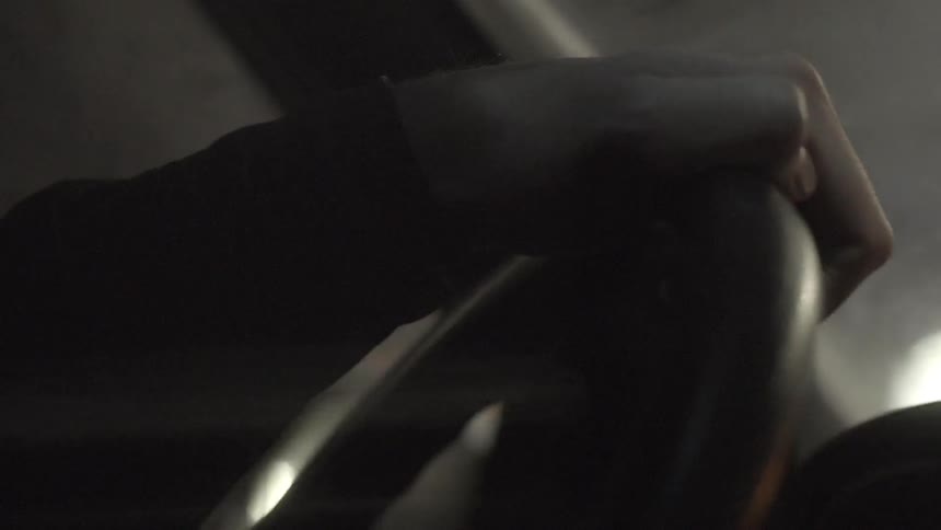 A person grips a steering wheel