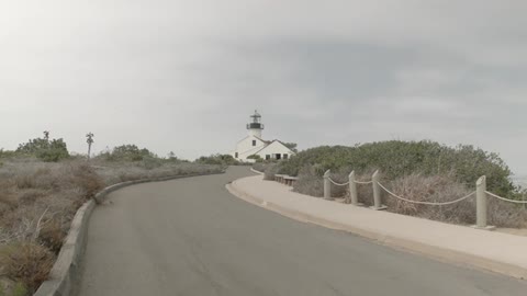Curving road leading to a lighthouse on a cloudy day