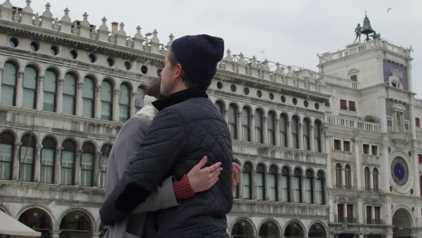 Couple hugging on a city street and what looks like a european city