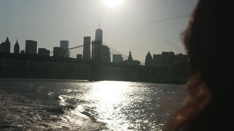 Woman on a boat viewing a city with the sun high in the sky